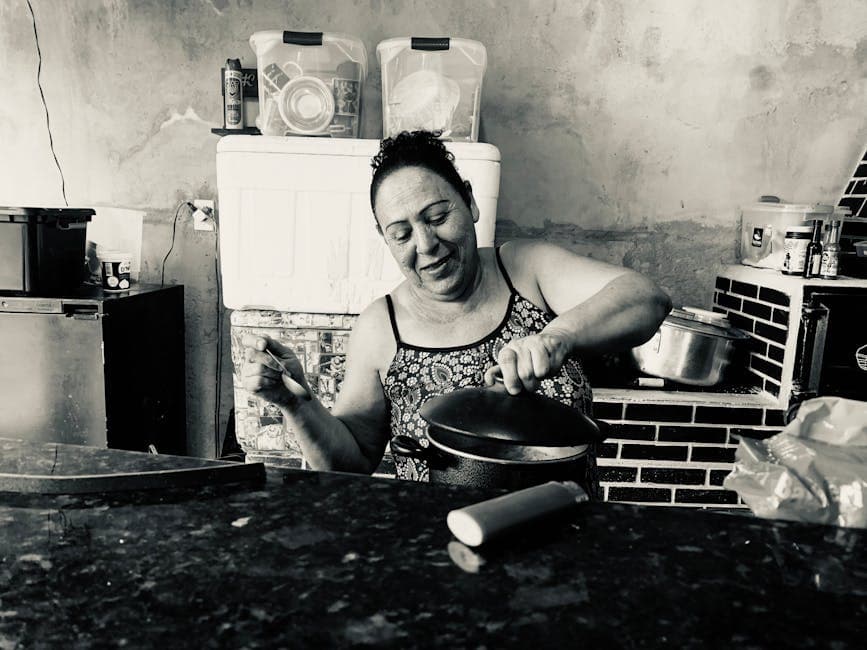 A woman joyfully cooks in a rustic kitchen in Serra do Cipó, Brazil.