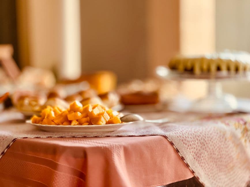 A close-up of a table with mango pieces and pastries in Anápolis, Brazil, with warm lighting.