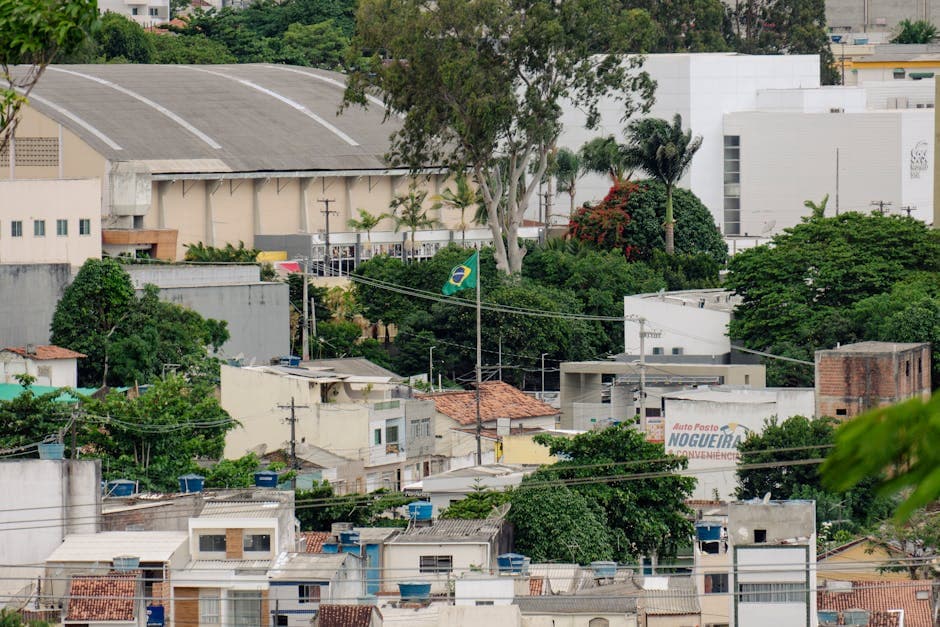 A vibrant urban view showcasing buildings and a prominent Brazilian flag among lush greenery.