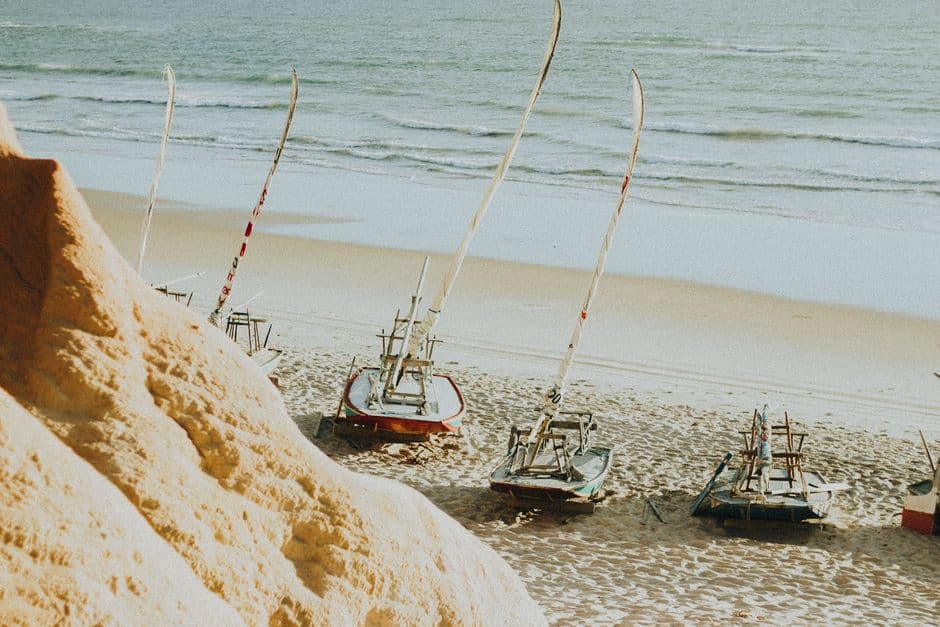 Jangadas resting on the sandy shores of Canoa Quebrada, Brazil, on a sunny summer day.