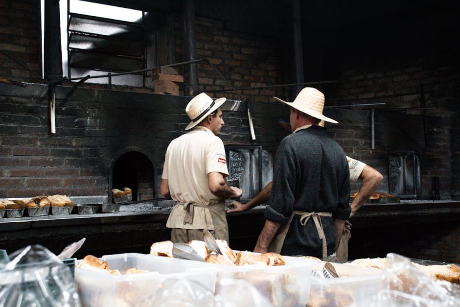 Bakers work together in a rustic setting with a wood-fired oven in Gramado, Brazil.