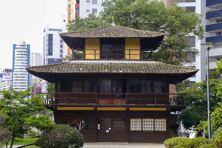 Traditional Japanese building in Curitiba's Praça do Japão amidst modern cityscape.