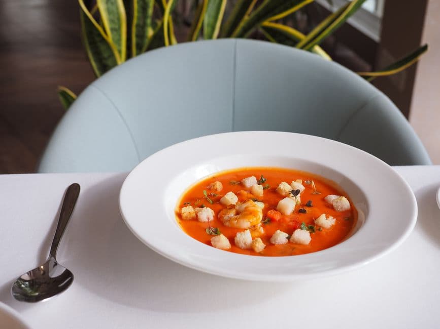 Elegant bowl of shrimp soup garnished with croutons, perfect for gourmet dining and food photography.