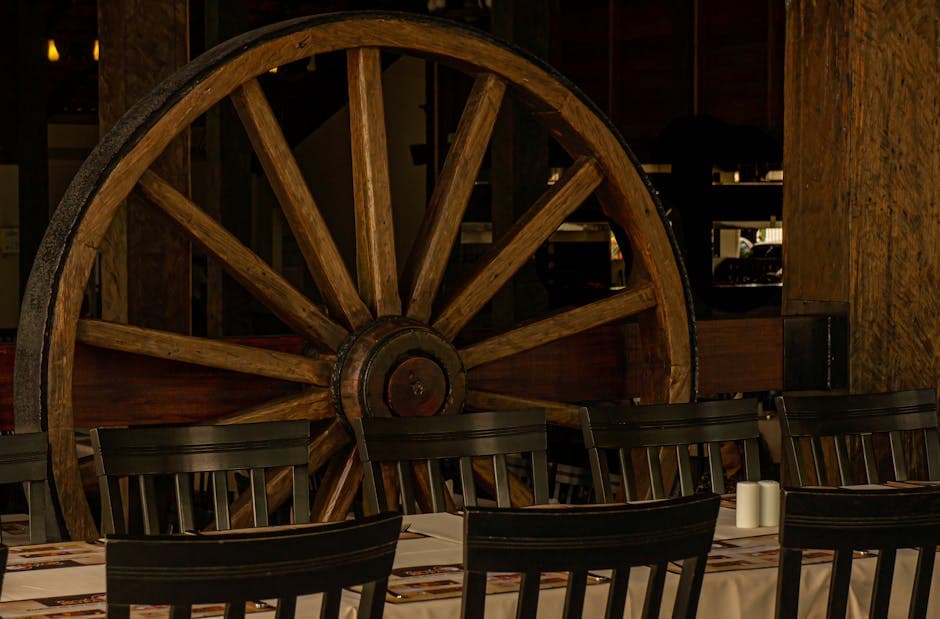 Cozy restaurant interior featuring a large wooden wheel and rustic wooden chairs.