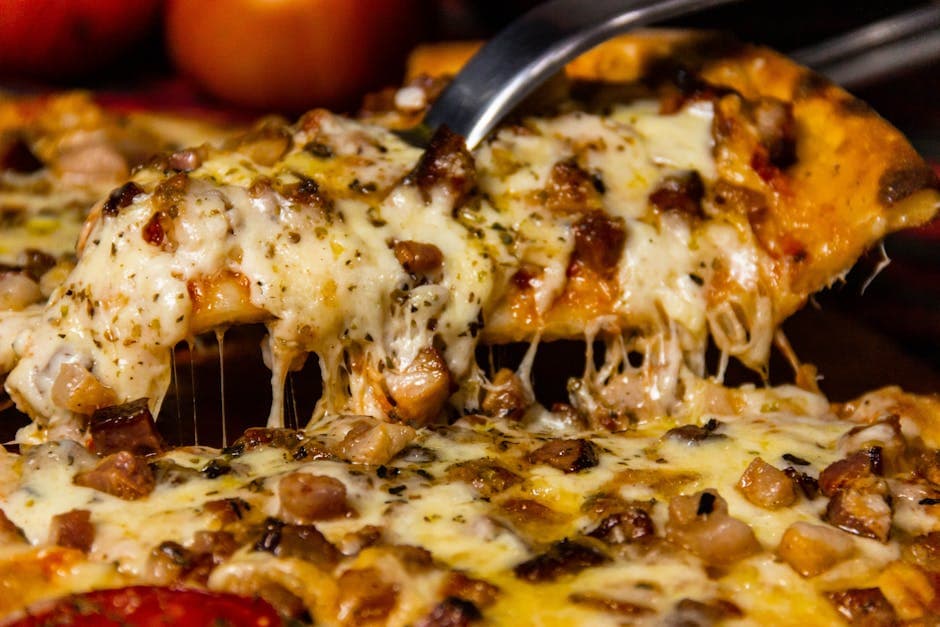 Delicious slice of cheesy pizza with toppings being served, mouth-watering close-up.