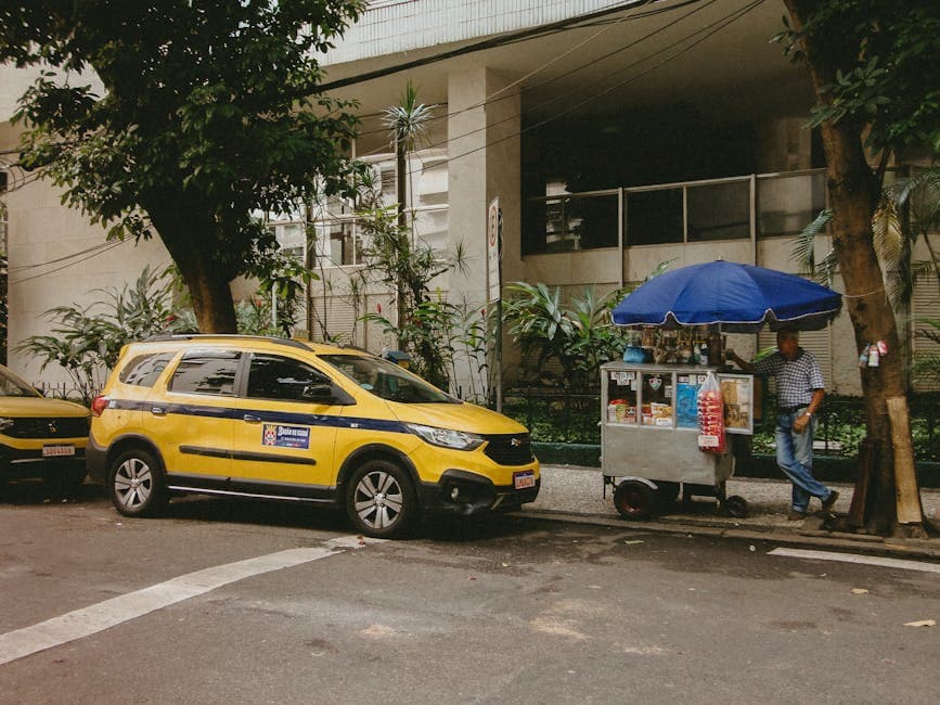 A typical street scene in Rio de Janeiro featuring a yellow taxi and a street vendor in front of a modern building.