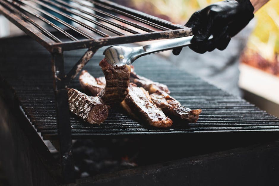 A person grilling delicious beef over a barbecue outdoors in Recife, Brazil.