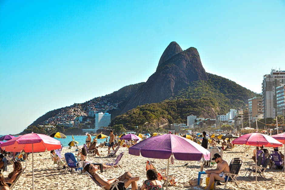 Vibrant beach day at Ipanema with mountain views and lively crowd enjoying the sun.