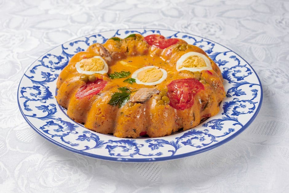Appetizing Cuscuz Paulista with eggs, peas, and tomatoes presented on a decorative blue and white plate.