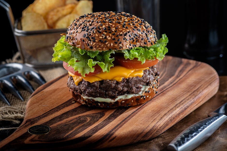Close-up of a delicious cheeseburger with sesame seed bun and toppings on a wooden board.