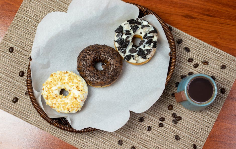 Overhead view of assorted donuts with coffee on a wooden table.