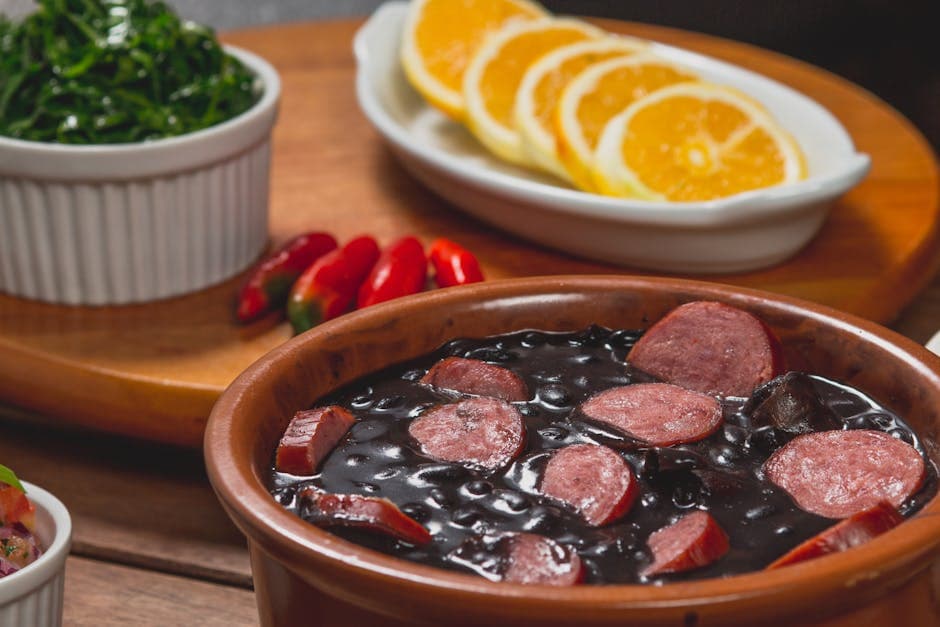 Traditional Brazilian feijoada with chorizo, orange slices, greens, and peppers.