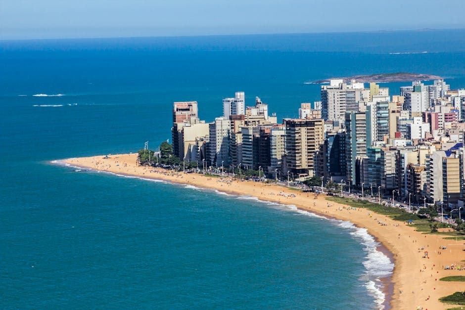 Aerial view of Vila Velha's coastline with skyscrapers and sandy beach, Brazil, vibrant summer scene.
