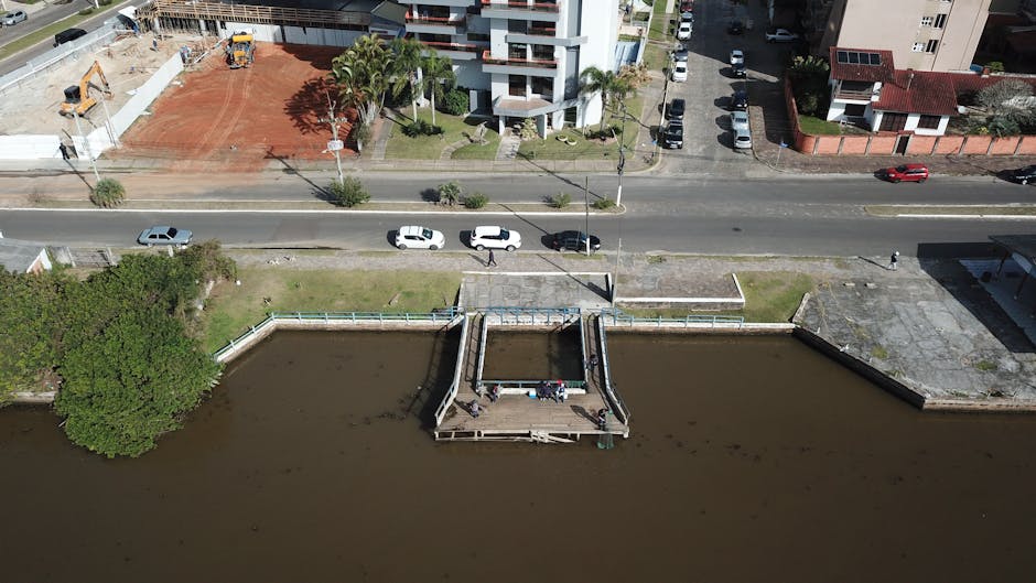 Aerial view of a dock near an urban landscape with parked cars and buildings.