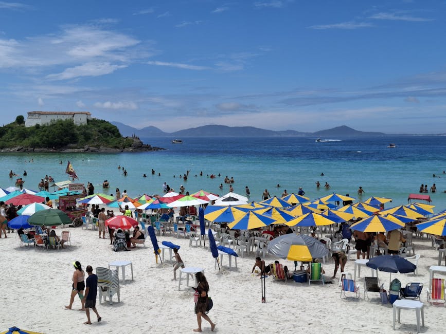 A lively beach with colorful umbrellas and people enjoying the sunny day.
