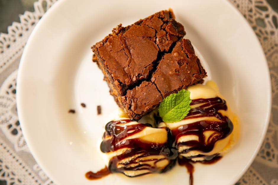 Top view of a decadent chocolate brownie served with vanilla ice cream and mint garnish.