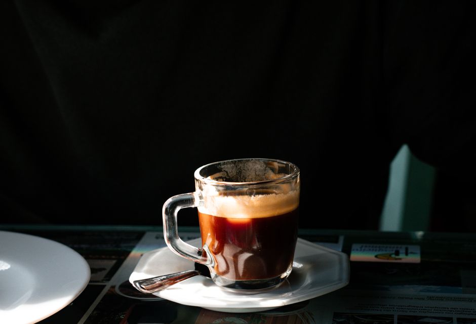A close-up of an espresso coffee served in a clear glass cup on a sunny day in São Paulo, Brazil.
