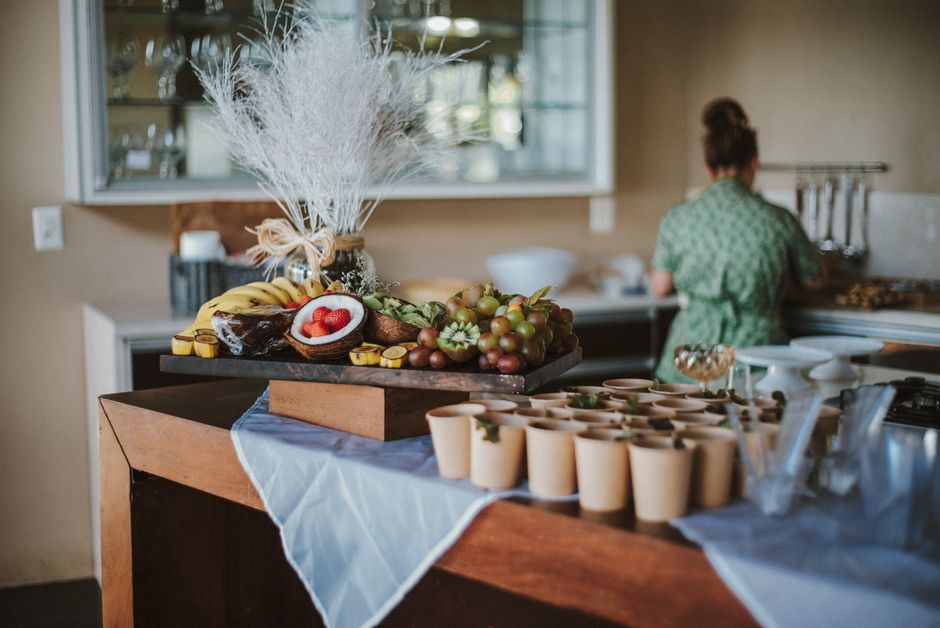 A beautifully arranged fruit platter with decorative elements on a kitchen counter, showcasing a mix of tropical fruits and serving cups.