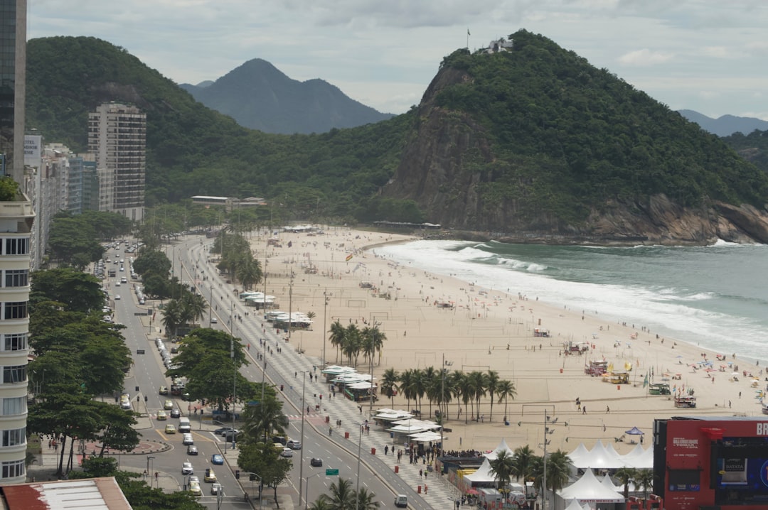 Busy beach with city buildings and green mountains.