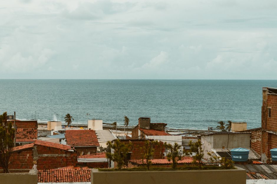 A picturesque view of rooftops and the ocean in Natal, Brazil, with an overcast sky.