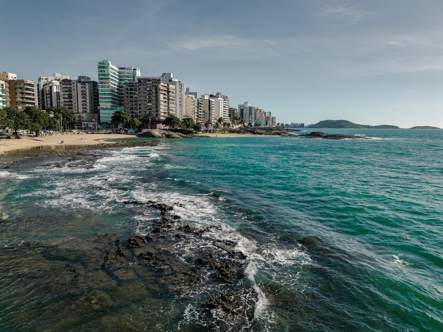 Scenic view of Guarapari's coastline with urban skyline and clear blue waters in Brazil.