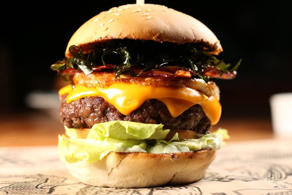 Close-up of a delicious gourmet cheeseburger with lettuce, bacon, and cheddar cheese.