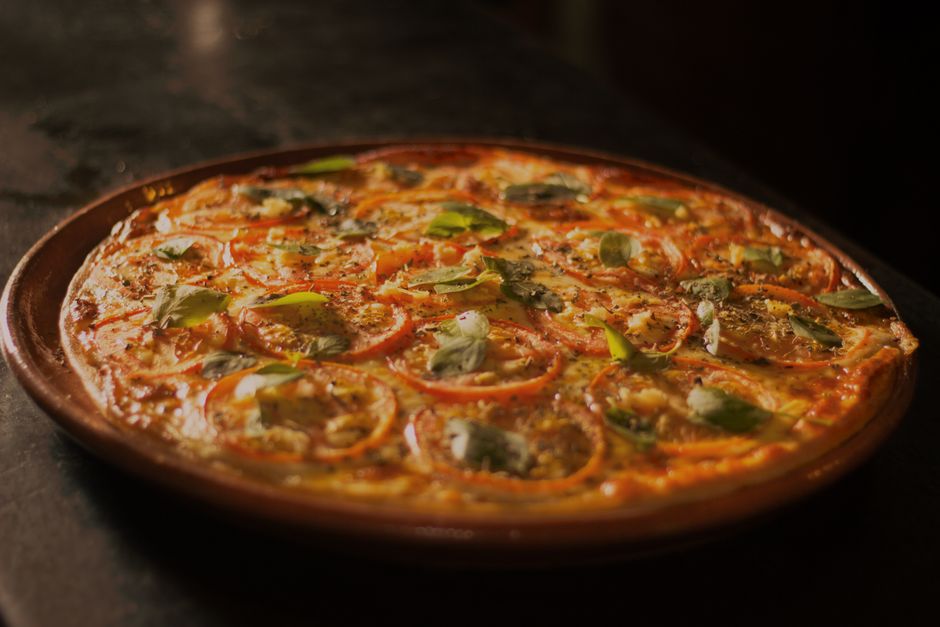 Close-up of a mouth-watering pizza topped with fresh basil, tomato, and mozzarella, capturing the essence of Italian cuisine.