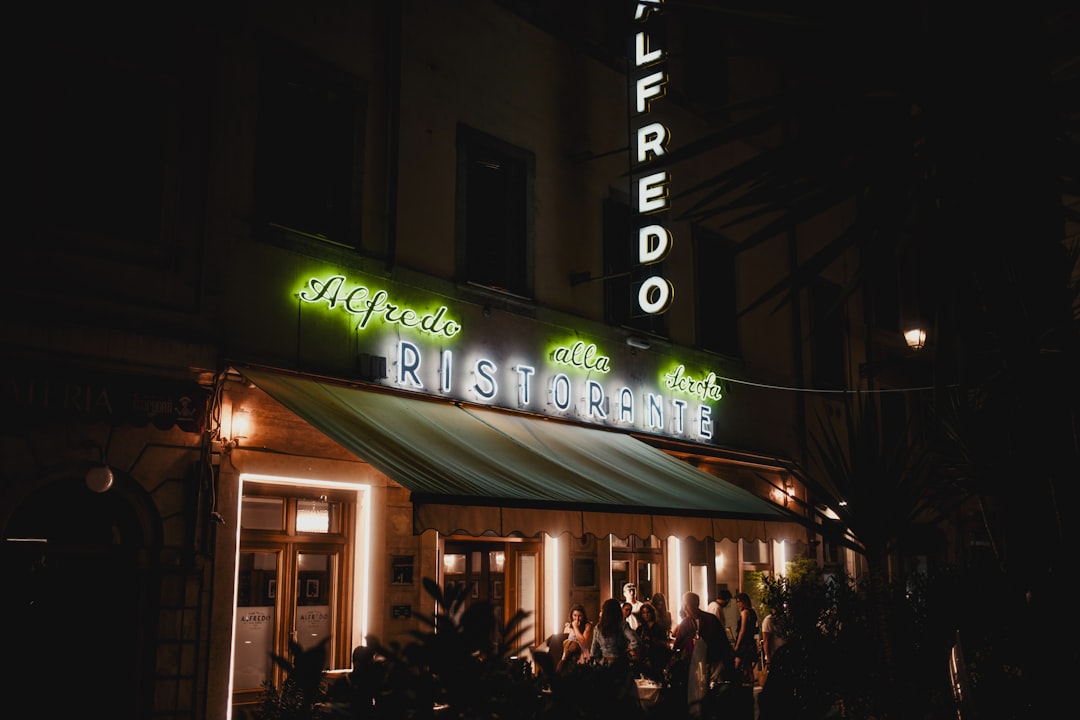 Restaurant alfredo lit up at night with people outside