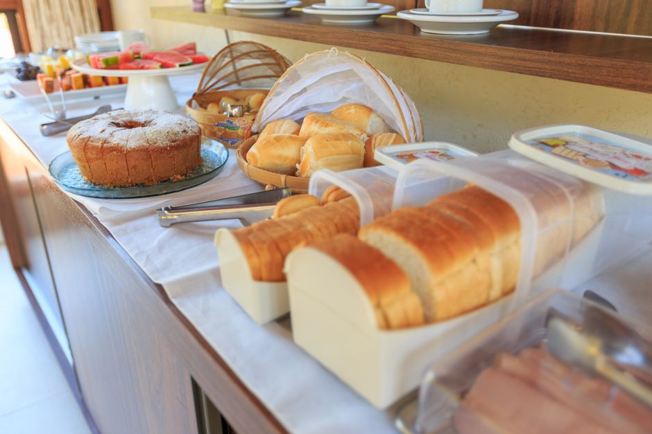 A sumptuous breakfast buffet with various breads, cakes, and fresh fruits displayed in a cozy indoor setting.