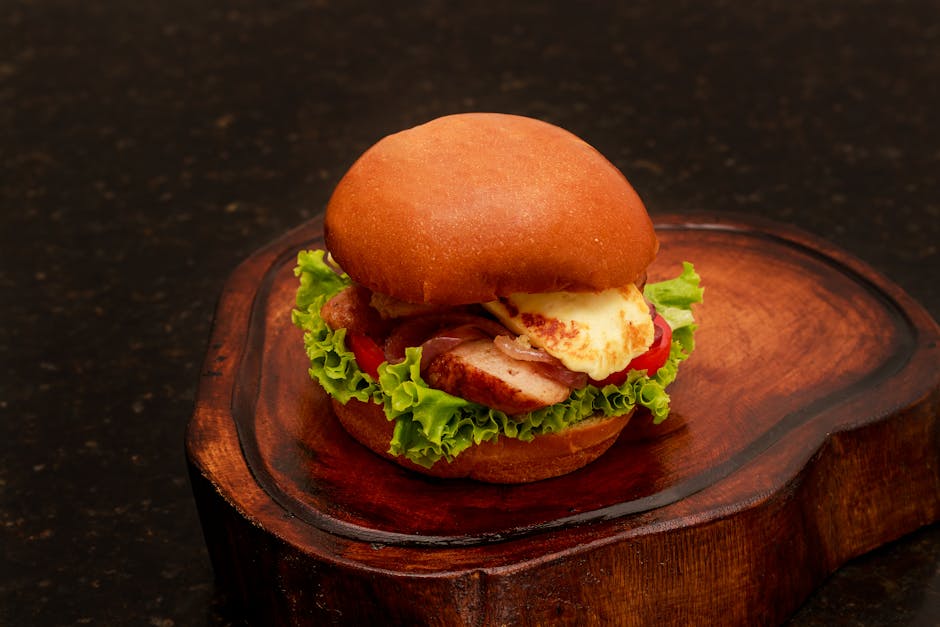 Appetizing chicken burger with lettuce and cheese on a wooden tray.