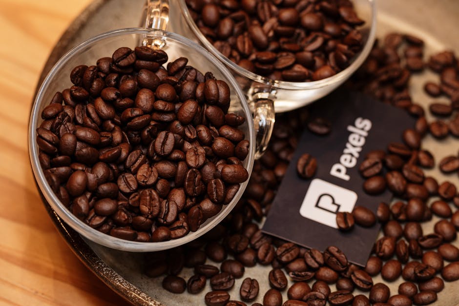 Close-up of coffee beans in clear glass cups on a rustic tray, ideal for food photography.