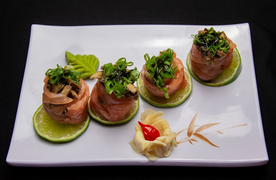 Elegant salmon sushi rolls garnished with greens on a lime slice in a fine dining setting.
