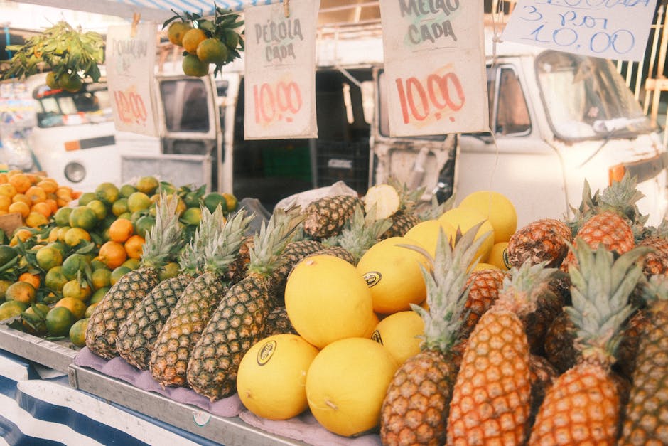 A colorful display of pineapples, melons, and oranges at an outdoor market. Great for travel and lifestyle themes.