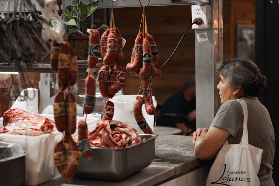 A woman browses hanging sausages and raw meat in an Argentine butcher shop.