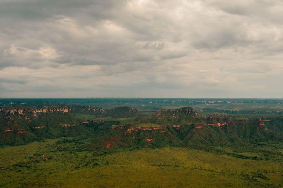 Stunning aerial shot of Serras Gerais' lush landscape in Tocantins, Brazil, featuring expansive green plains and rugged cliffs.