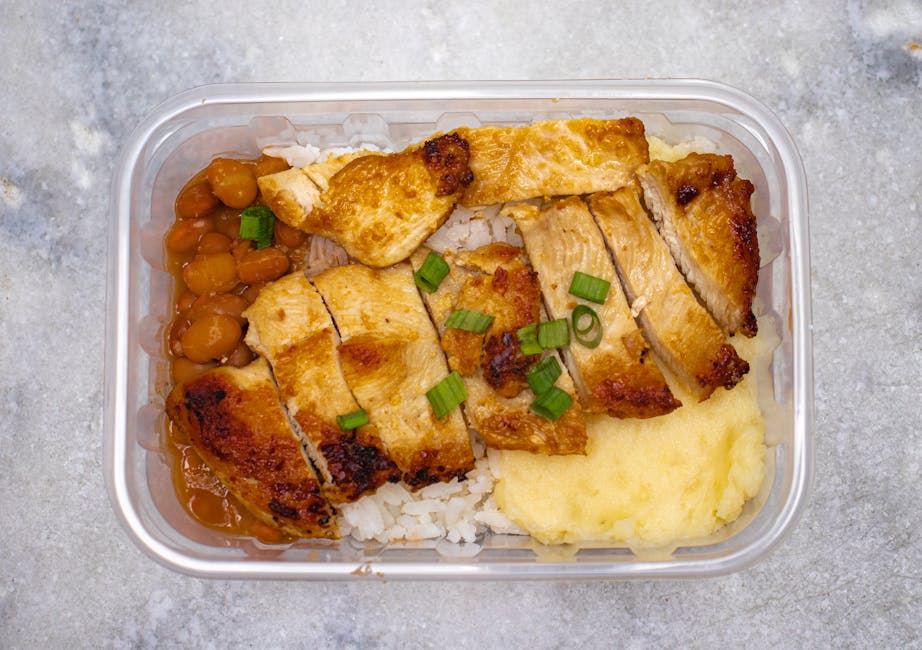 Grilled chicken with rice, beans, and mashed potatoes in a takeout container.