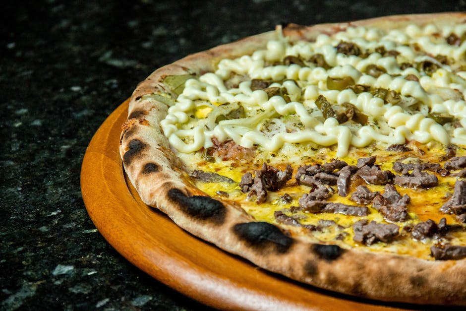 Close-up of a flavorful beef and cheese pizza topped with mayonnaise and olives.