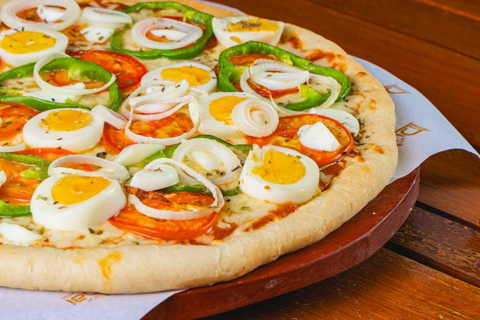 Delicious pizza topped with eggs, onions, peppers, and tomatoes on wooden board.