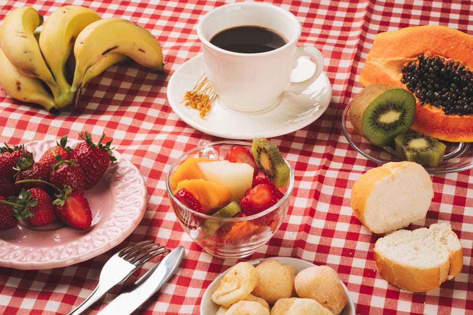Delicious breakfast table with coffee, fresh fruits, and bread on a checkered tablecloth.