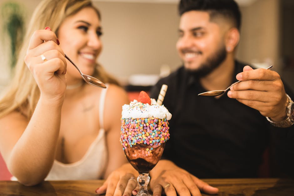 A joyful couple sharing a vibrant dessert in a relaxed indoor setting.