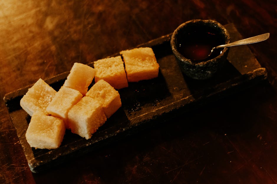 Crispy Brazilian tapioca cubes served with a savory dip on a rustic stone tray.