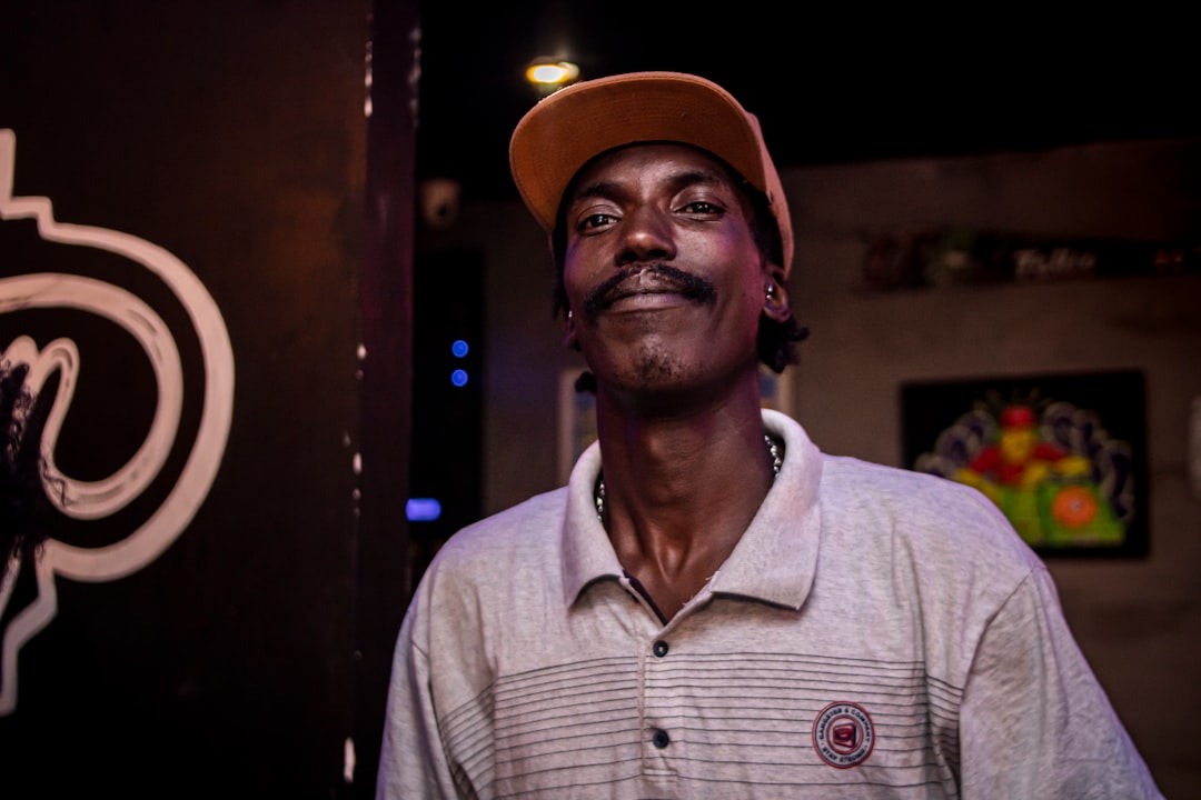 a man in a hat standing in front of a sign
