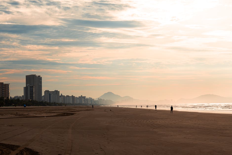Scenic view of São Vicente beach at dusk with city skyline and mountains in Brazil.