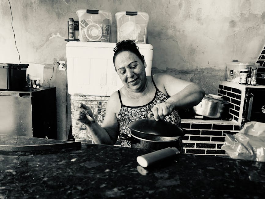 A woman joyfully cooks in a rustic kitchen in Serra do Cipó, Brazil.
