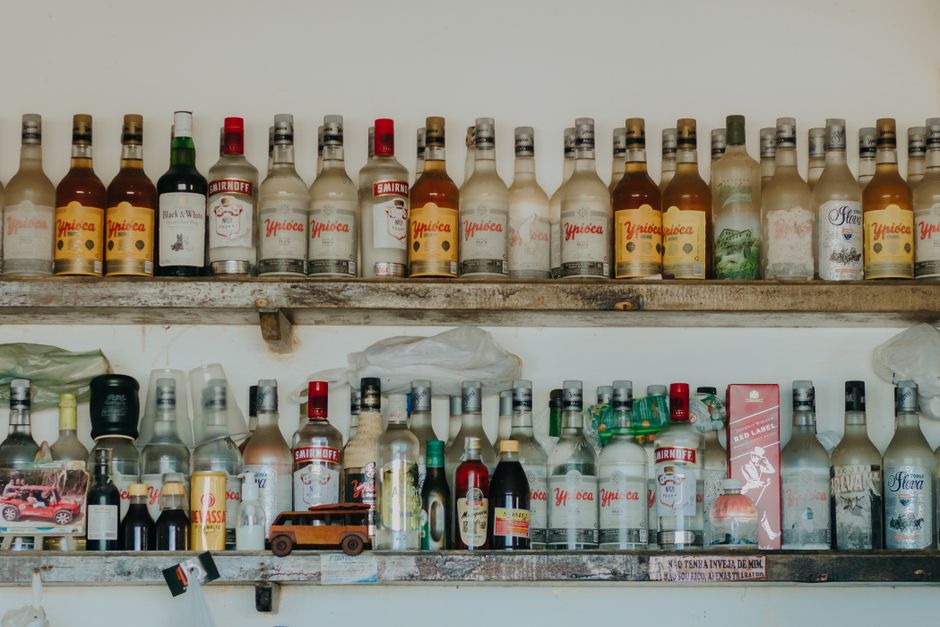 A display of various alcoholic bottles neatly arranged on rustic wooden shelves.